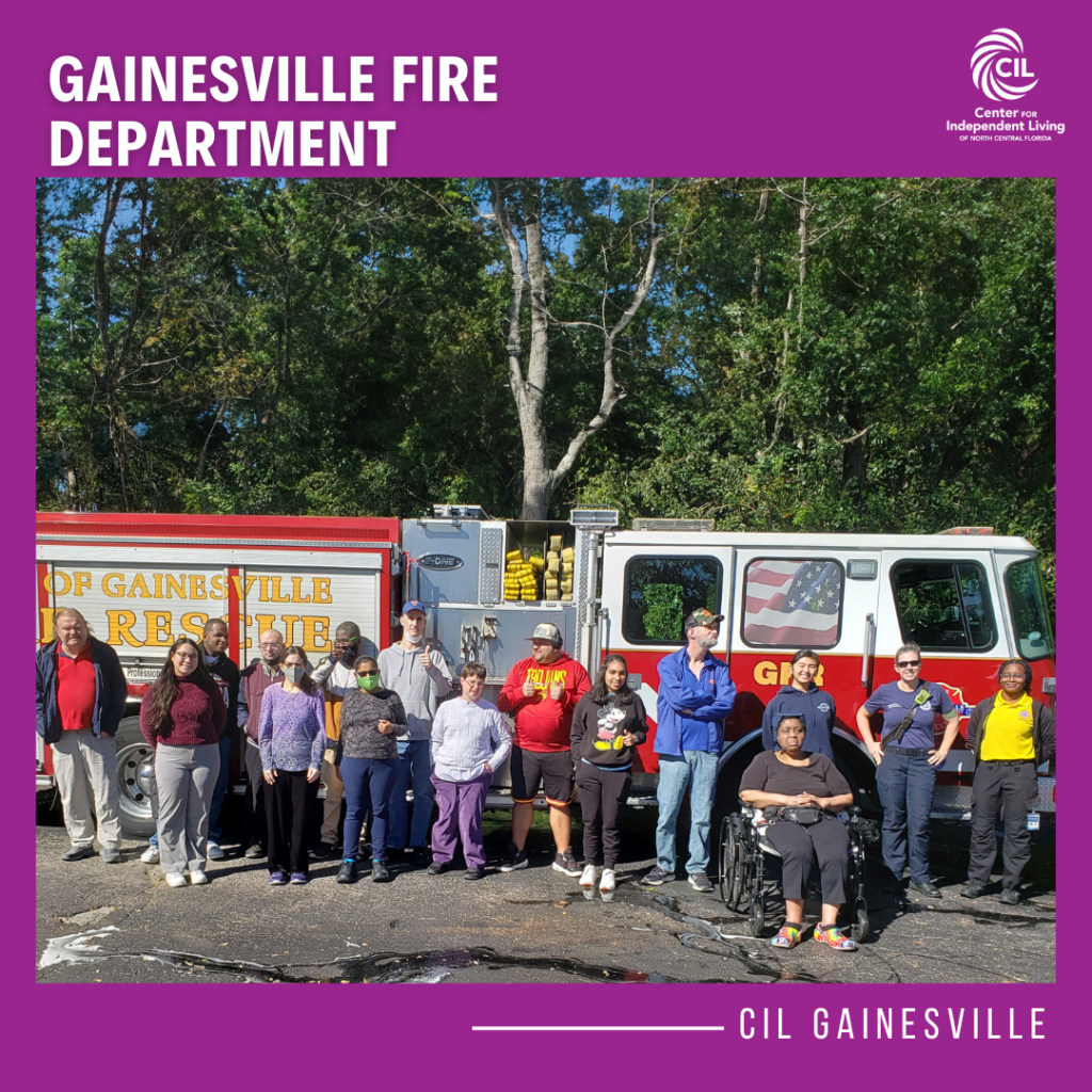 This image shows a group of people standing together in front of a Gainesville Fire Rescue truck. The group includes participants from the CIL Gainesville office and firefighters. The truck is red and white, with the words "Gainesville Fire Rescue" prominently displayed on its side, along with an American flag design on one of the windows. Some individuals in the group are seated, including one person in a wheelchair, while others are standing. The setting appears to be outdoors with trees in the background. The image features a purple border with the text "GAINESVILLE FIRE DEPARTMENT" at the top and "CIL GAINESVILLE" at the bottom, along with the logo of the Center for Independent Living of North Central Florida in the corner.